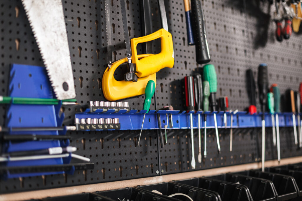 Tools like screwdrivers, saws, and hammers neatly organized on a pegboard in a storage shed, ideal for winter preparation. recommended by storage tips and advice